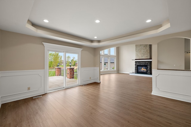 66701 Notre Dame Blvd, Washington, MI 48095 - unfurnished living room featuring a tray ceiling, a stone fireplace, wood finished floors, wainscoting, and recessed lighting