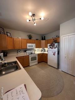 4412 Aster Blvd, Howell, MI 48843 - kitchen featuring white appliances, a sink, light countertops, brown cabinets, and a chandelier