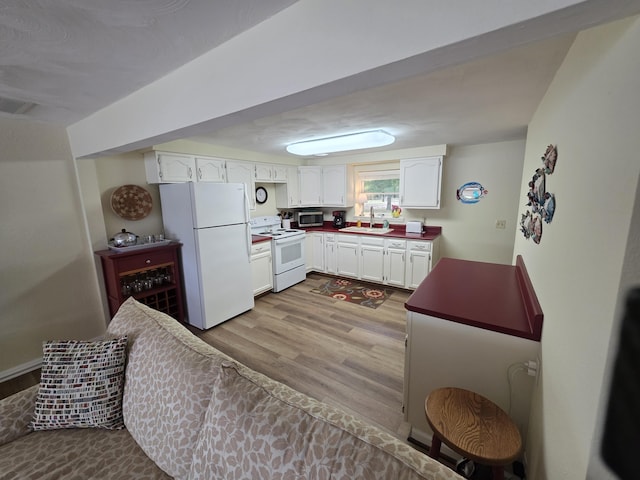 5022 N Ford Lake Rd, Fountain, MI 49410 - kitchen featuring white appliances, a sink, wood finished floors, white cabinetry, and dark countertops