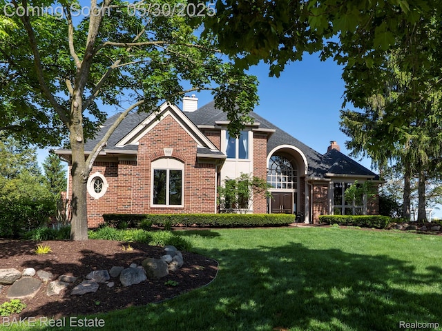966 Mcdonald Dr, Northville, MI 48167 - view of front of house with brick siding, a chimney, a front lawn, and a shingled roof
