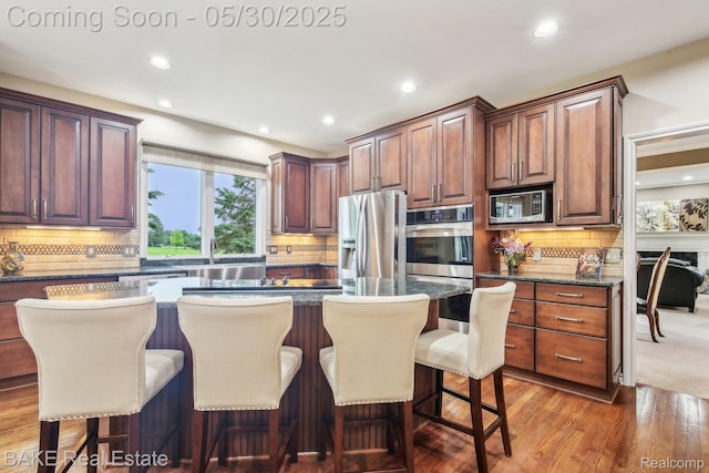 966 Mcdonald Dr, Northville, MI 48167 - kitchen with appliances with stainless steel finishes, tasteful backsplash, a breakfast bar area, wood finished floors, and recessed lighting
