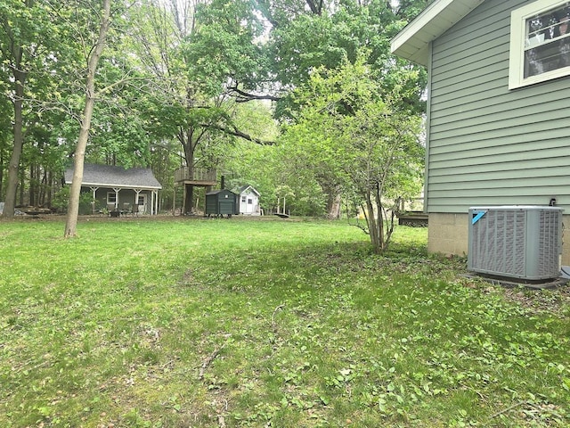 3775 N Hemlock Rd, Hemlock, MI 48626 - view of green lawn featuring central AC, an outbuilding, and view of scattered trees