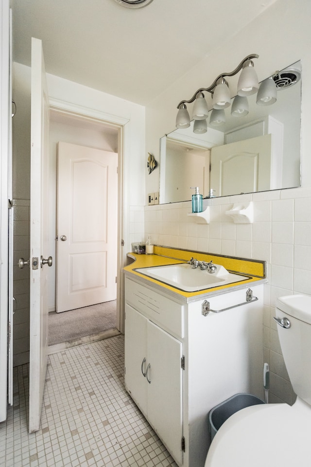 bathroom featuring vanity, toilet, tile walls, and tile patterned flooring