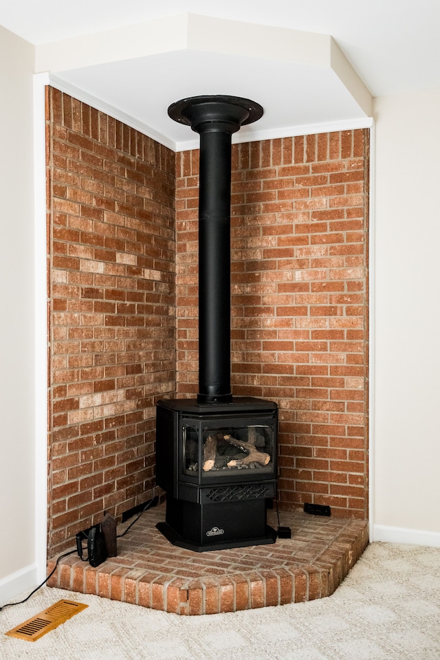 detailed view of a wood stove, carpet, and baseboards