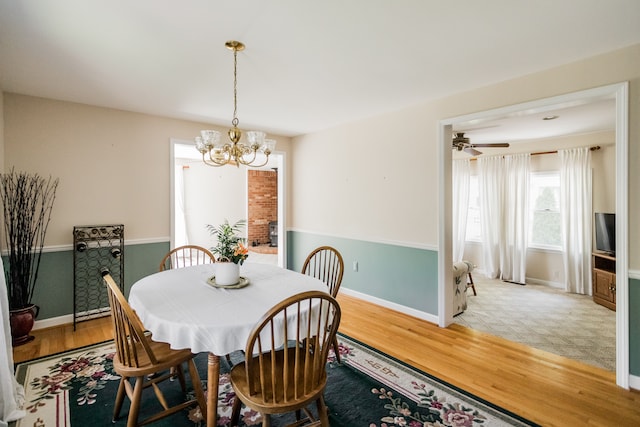dining room featuring a chandelier, baseboards, light wood finished floors, and a ceiling fan