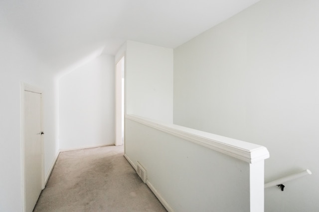 corridor featuring light colored carpet and an upstairs landing