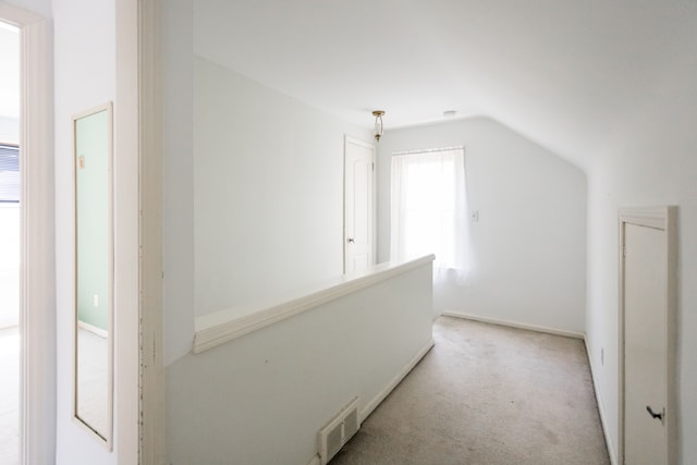 hall featuring carpet, an upstairs landing, and vaulted ceiling