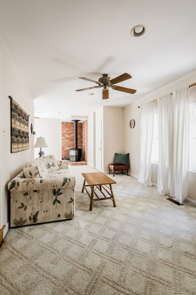 carpeted living area with a wood stove, a ceiling fan, recessed lighting, and baseboards