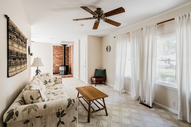 living room featuring a wood stove, plenty of natural light, baseboards, and ceiling fan