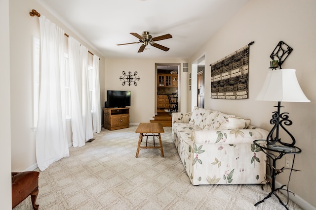 living room with ceiling fan, light carpet, and baseboards