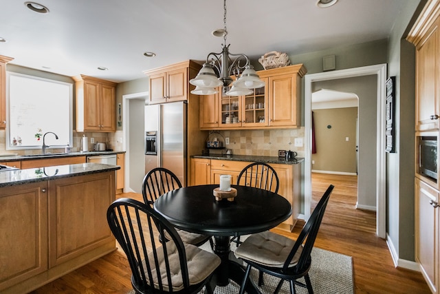 dining room featuring arched walkways, baseboards, wood finished floors, a chandelier, and recessed lighting