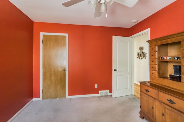 bedroom featuring light colored carpet, baseboards, and a ceiling fan