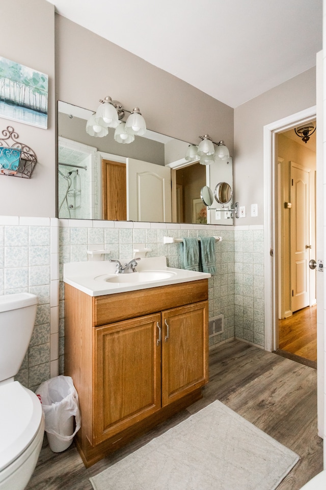 full bathroom featuring tile walls, toilet, wood finished floors, wainscoting, and vanity