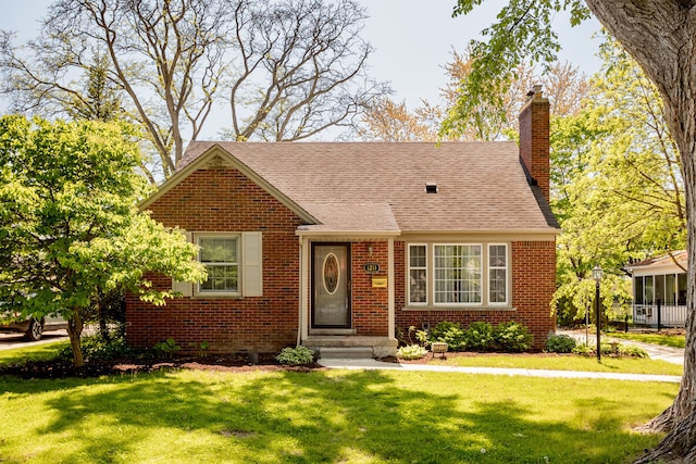view of front of house with brick siding, a front lawn, and a chimney
