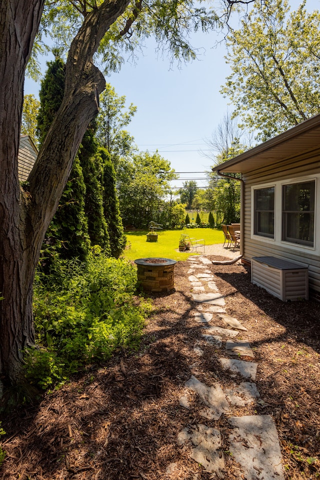 view of grassy yard featuring an outdoor fire pit