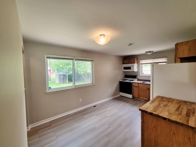 16442 Brandt St, Romulus, MI 48174 - kitchen featuring white appliances, brown cabinets, light wood-style floors, baseboards, and butcher block counters