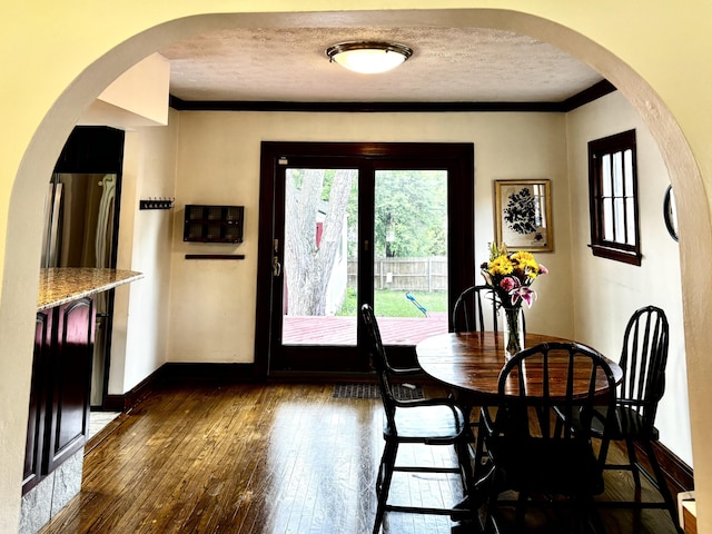 404 Pauline Blvd, Ann Arbor, MI 48103 - dining room featuring a textured ceiling, dark wood-style floors, ornamental molding, baseboards, and arched walkways