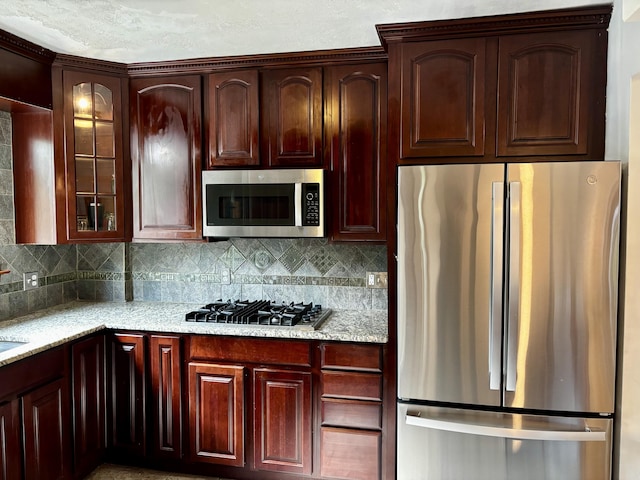 404 Pauline Blvd, Ann Arbor, MI 48103 - kitchen with stainless steel appliances, tasteful backsplash, glass insert cabinets, light stone counters, and dark brown cabinets