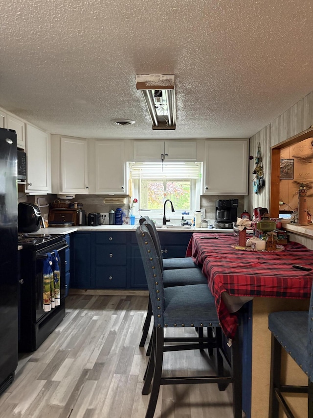 8000 Derry Rd, Vestaburg, MI 48891 - kitchen with black appliances, a sink, light wood-style flooring, white cabinetry, and a textured ceiling