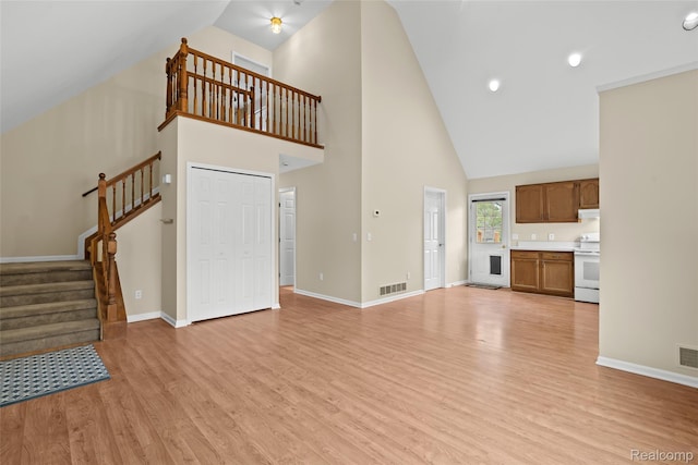 3819 Hazelett Dr, Waterford, MI 48328 - unfurnished living room with high vaulted ceiling, light wood finished floors, baseboards, and stairway