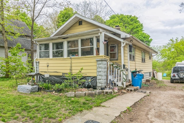 526 S Front St, Dowagiac, MI 49047 - view of front of property with a chimney, dirt driveway, and a sunroom