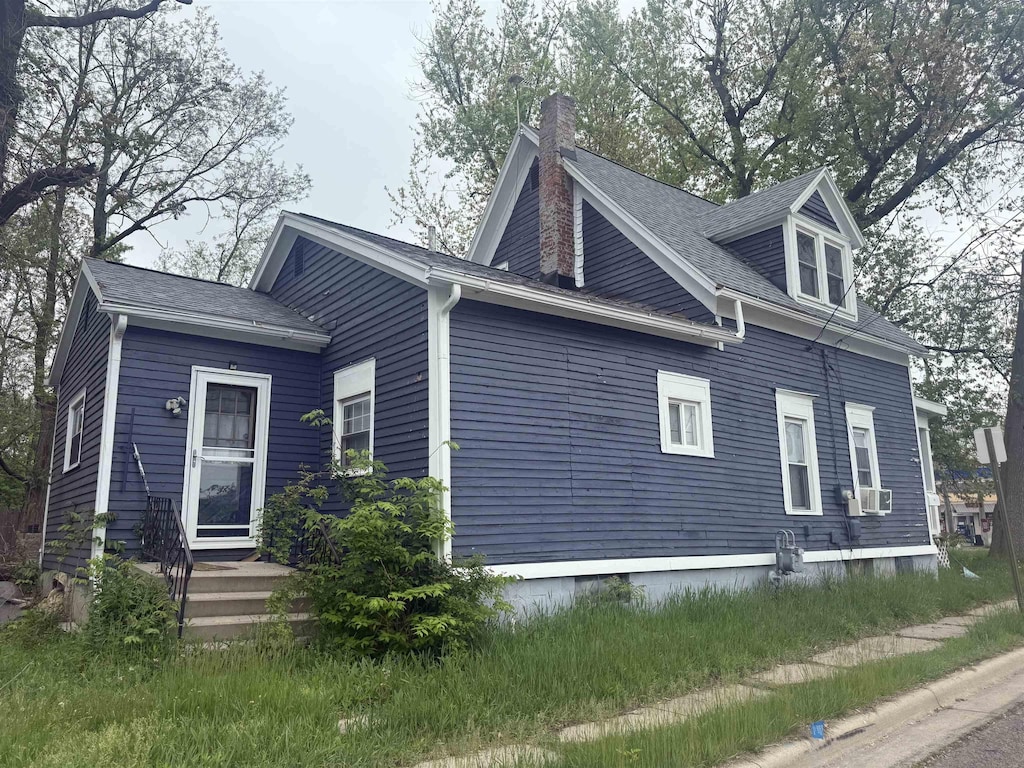 598 S Main St, Adrian, MI 49221 - view of home's exterior featuring a chimney, cooling unit, and a shingled roof