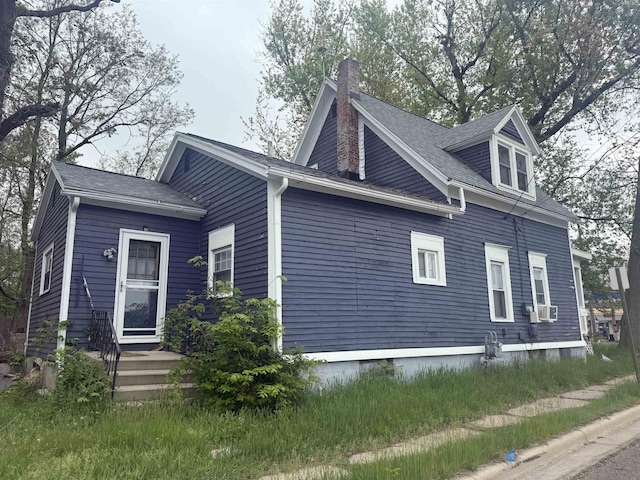 598 S Main St, Adrian, MI 49221 - view of home's exterior featuring a chimney, cooling unit, and a shingled roof