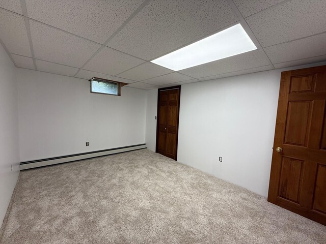 6035 W Trails End Rd, Ludington, MI 49431 - basement with a baseboard radiator, a paneled ceiling, and carpet floors
