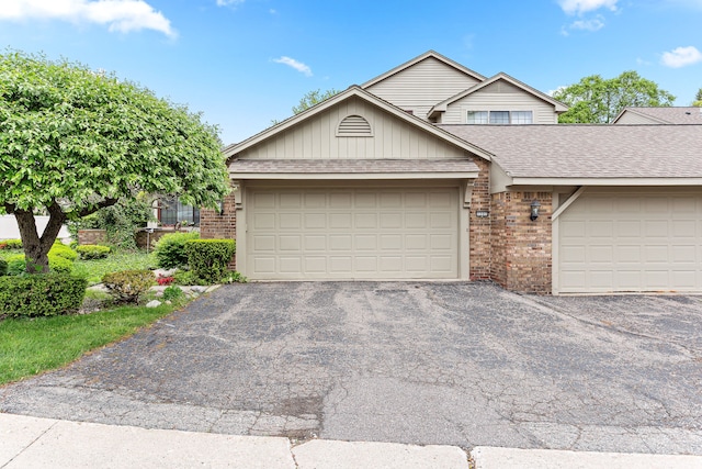 view of front facade with brick siding, driveway, a shingled roof, and an attached garage
