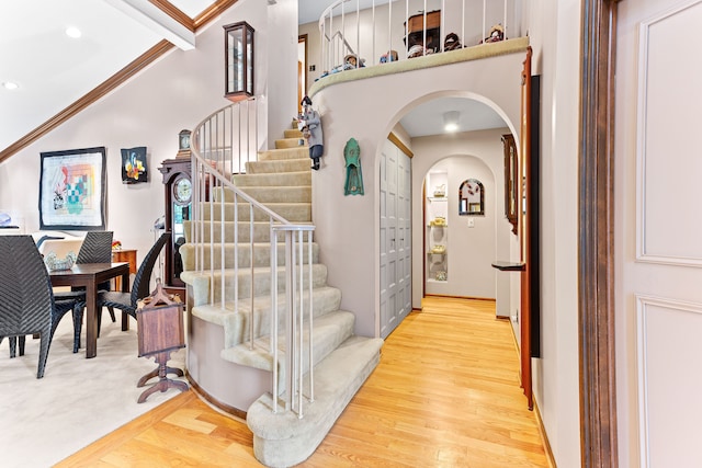 stairs with arched walkways, wood finished floors, and recessed lighting