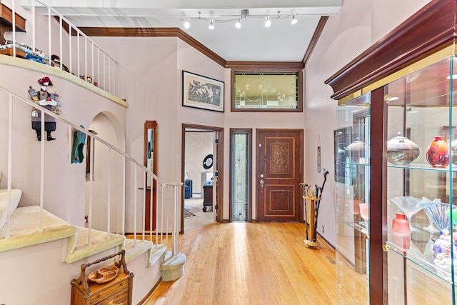 entrance foyer with stairway, ornamental molding, and wood finished floors