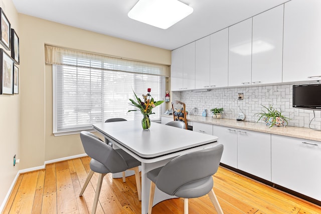 kitchen with decorative backsplash, light wood-style flooring, white cabinets, and baseboards