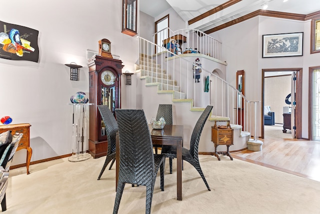 carpeted dining area with a high ceiling, stairs, and baseboards
