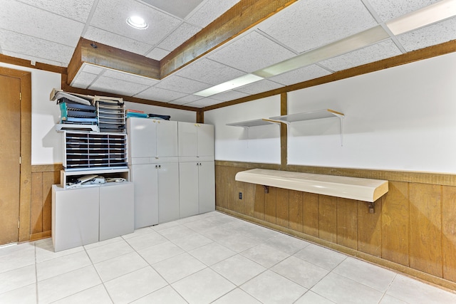 empty room with a wainscoted wall, a drop ceiling, and wood walls