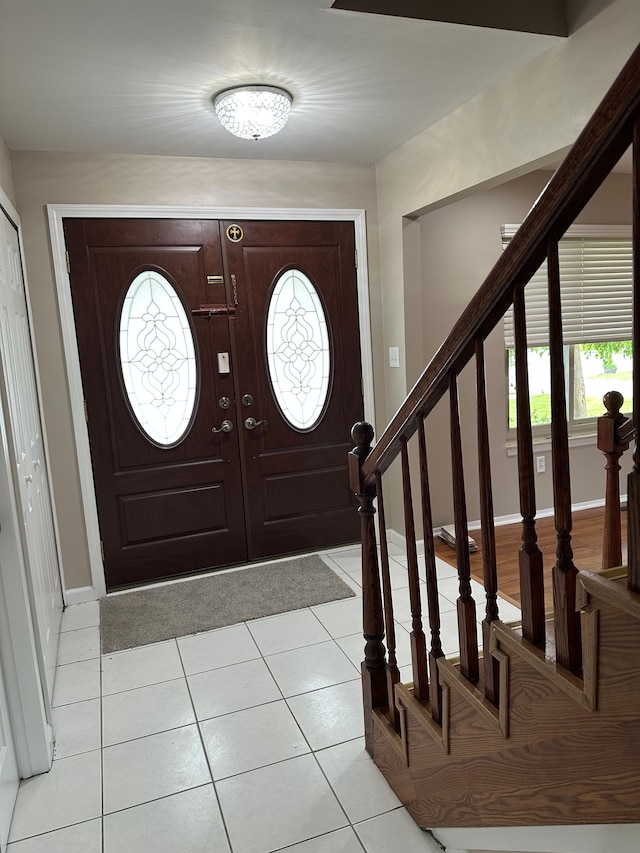 foyer featuring healthy amount of natural light, stairs, baseboards, and light tile patterned flooring