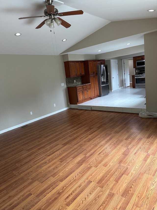 unfurnished living room with light wood-style flooring, vaulted ceiling, a ceiling fan, recessed lighting, and baseboards
