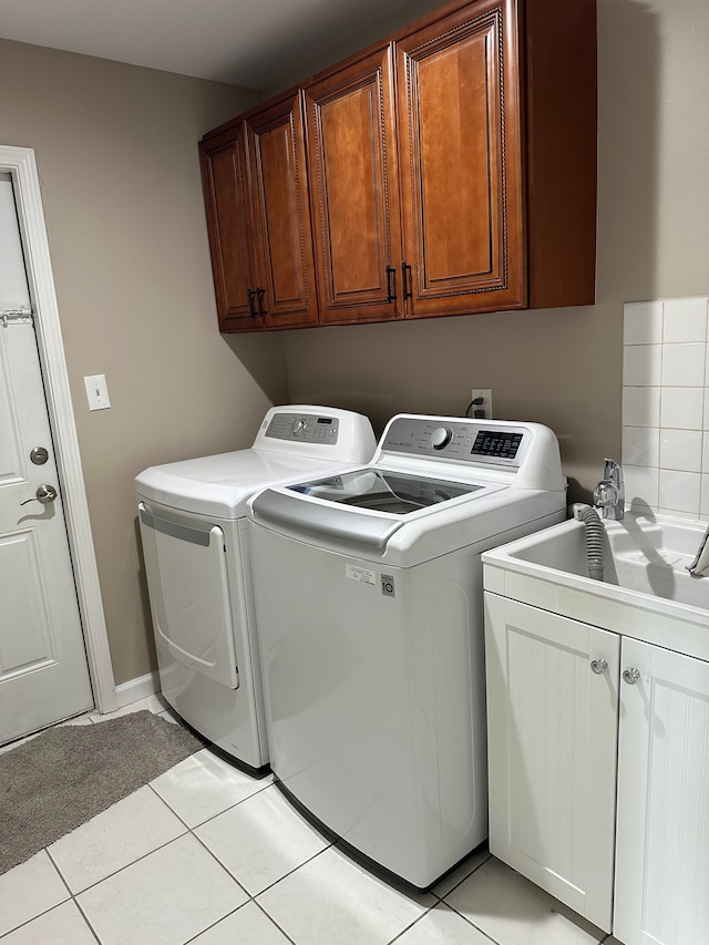 clothes washing area with cabinet space, washer and dryer, and light tile patterned floors