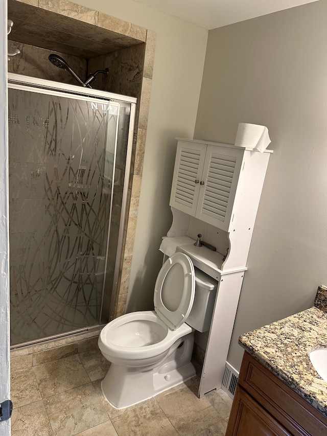 bathroom featuring vanity, toilet, a shower stall, and stone finish flooring