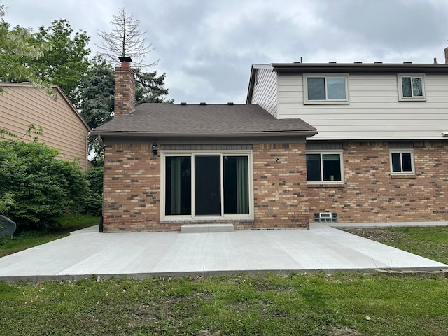 rear view of house featuring brick siding, a patio area, and a chimney