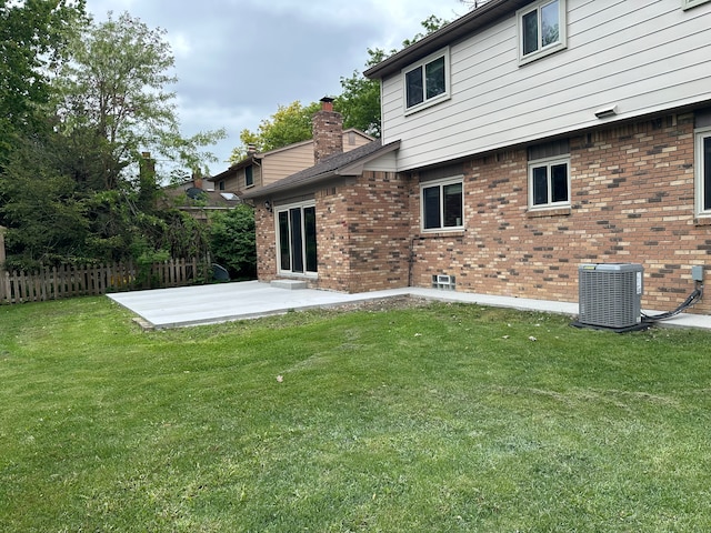 rear view of house featuring central AC, brick siding, a patio area, and a chimney