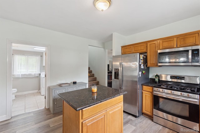 5160 N Milford Rd, Highland, MI 48356 - kitchen with stainless steel appliances, a center island, dark stone countertops, and light wood-type flooring