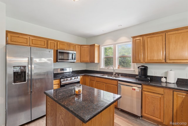 5160 N Milford Rd, Highland, MI 48356 - kitchen featuring appliances with stainless steel finishes, a sink, light wood-style flooring, dark stone counters, and a kitchen island