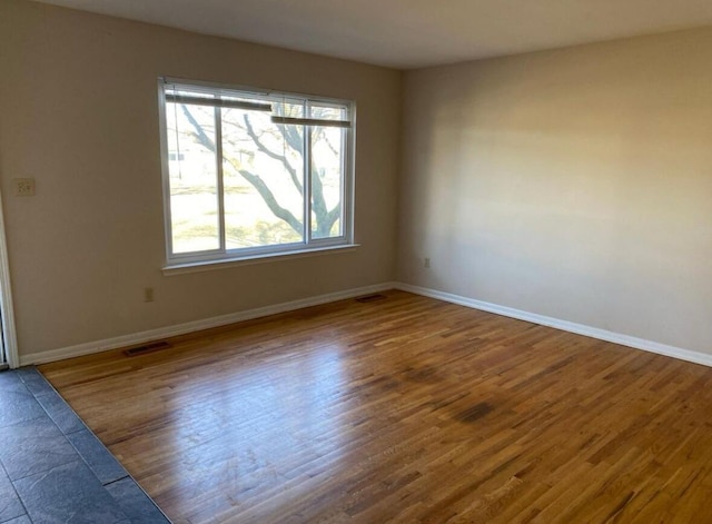 spare room with wood finished floors and baseboards