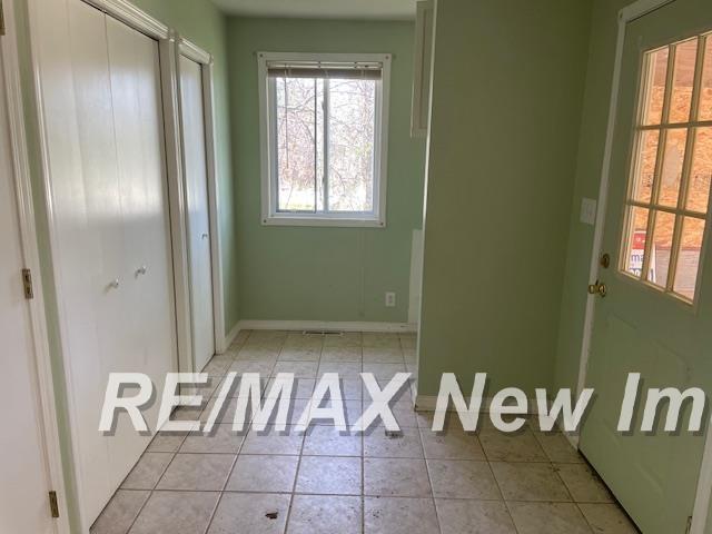 1944 S M 18 Hwy, Gladwin, MI 48624 - unfurnished bedroom with light tile patterned flooring, baseboards, and a closet