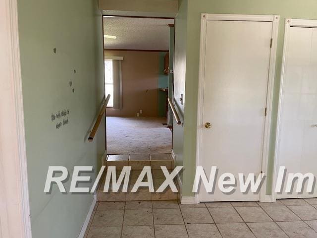 1944 S M 18 Hwy, Gladwin, MI 48624 - corridor with a textured ceiling, light tile patterned floors, baseboards, and light colored carpet