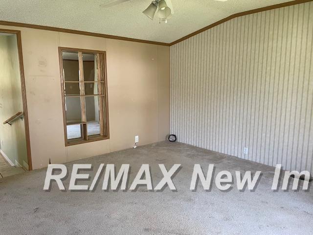 1944 S M 18 Hwy, Gladwin, MI 48624 - carpeted empty room with ornamental molding, ceiling fan, and a textured ceiling