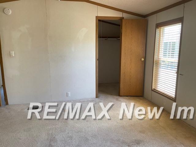 1944 S M 18 Hwy, Gladwin, MI 48624 - unfurnished bedroom featuring lofted ceiling, carpet flooring, and ornamental molding