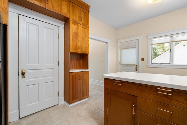 1054 Ferdon Rd, Ann Arbor, MI 48104 - kitchen with brown cabinets, light countertops, light tile patterned floors, baseboards, and refrigerator