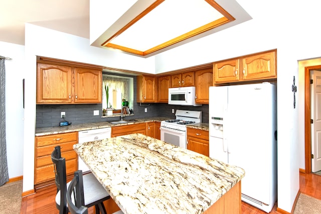906 Village Dr, Davison, MI 48423 - kitchen with white appliances, a sink, decorative backsplash, a breakfast bar area, and light wood-style flooring