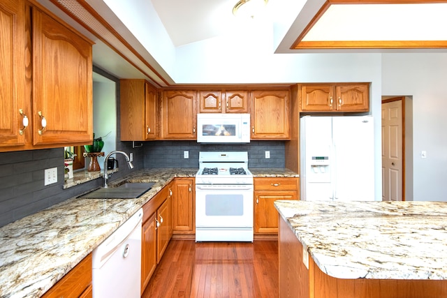 906 Village Dr, Davison, MI 48423 - kitchen featuring white appliances, vaulted ceiling, a sink, light stone counters, and brown cabinets